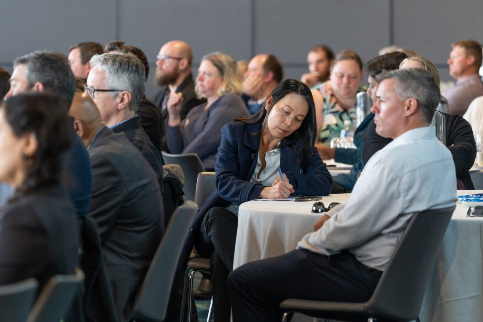 Woman writing notes during a conference.